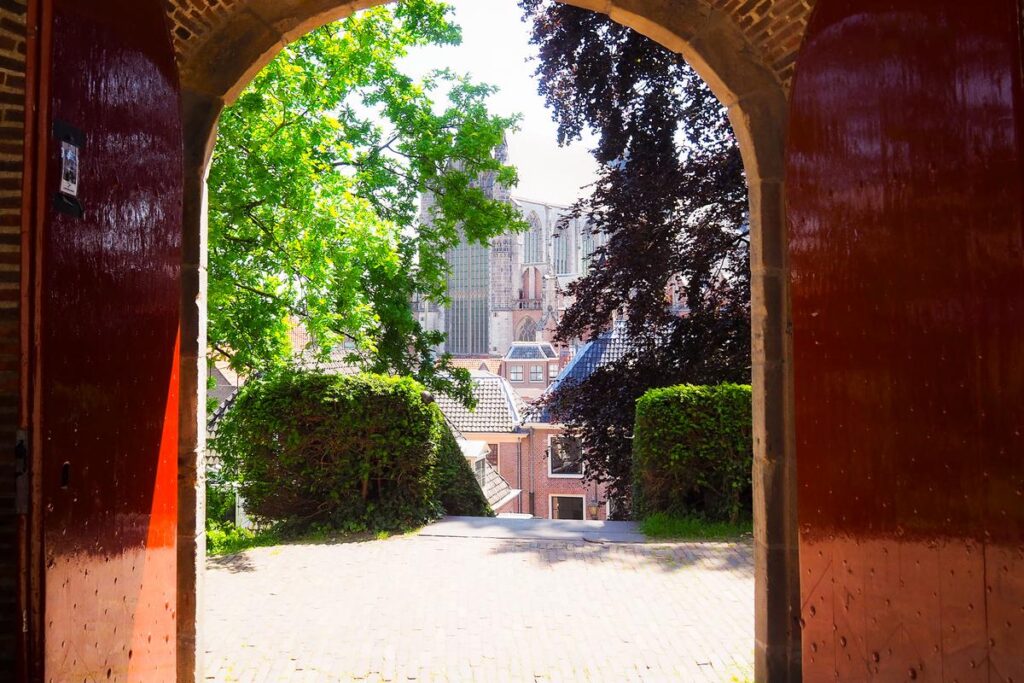 Historic exit view from Burcht van Leiden, showcasing traditional brick archway and verdant courtyard in the Netherlands.