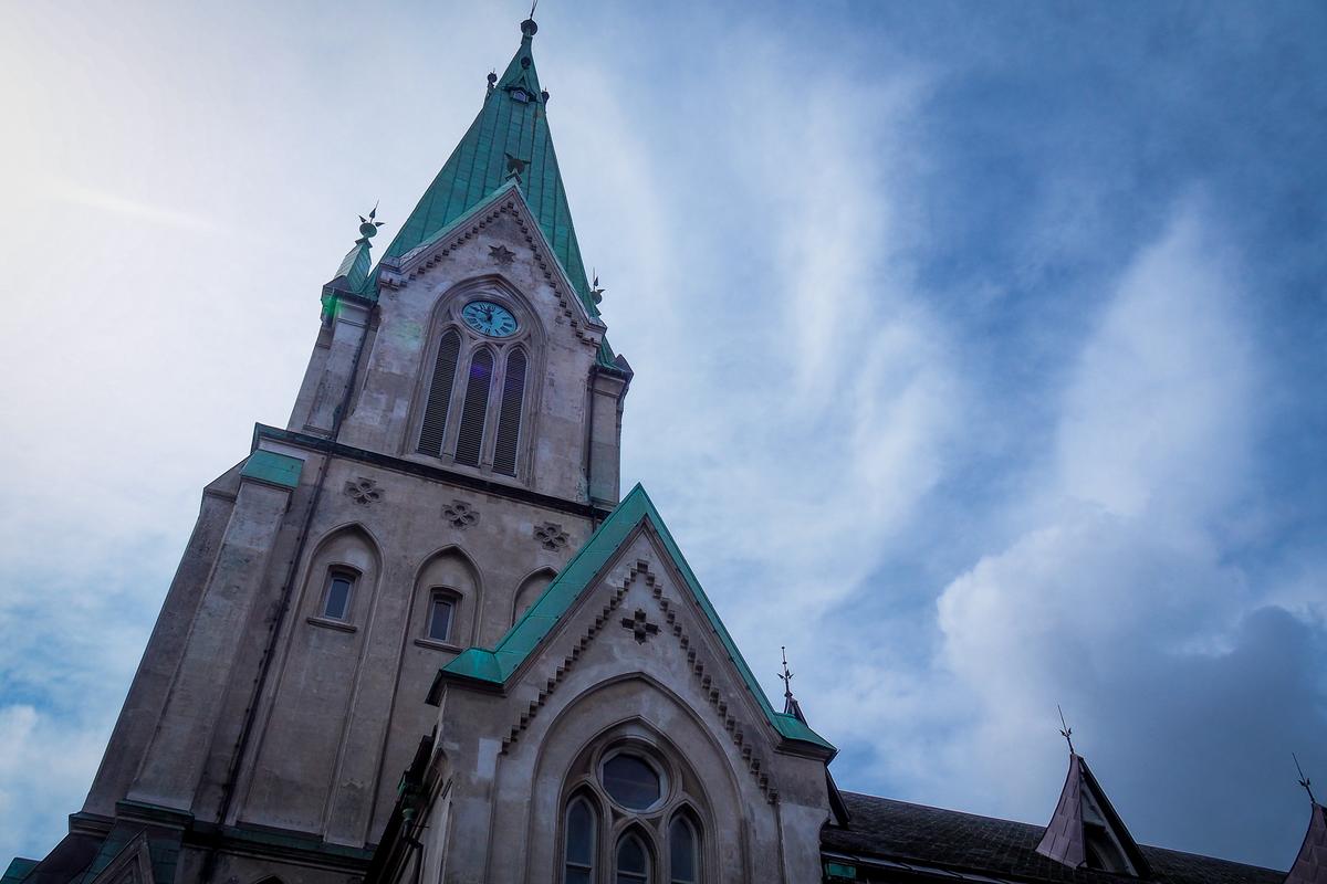 Historic Kristiansand Cathedral in Norway with Gothic Revival architecture against blue sky.