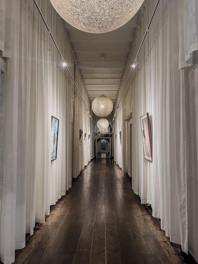 Elegant Hotel Arena Amsterdam hallway with artistic decor and striking chandeliers in lobby
