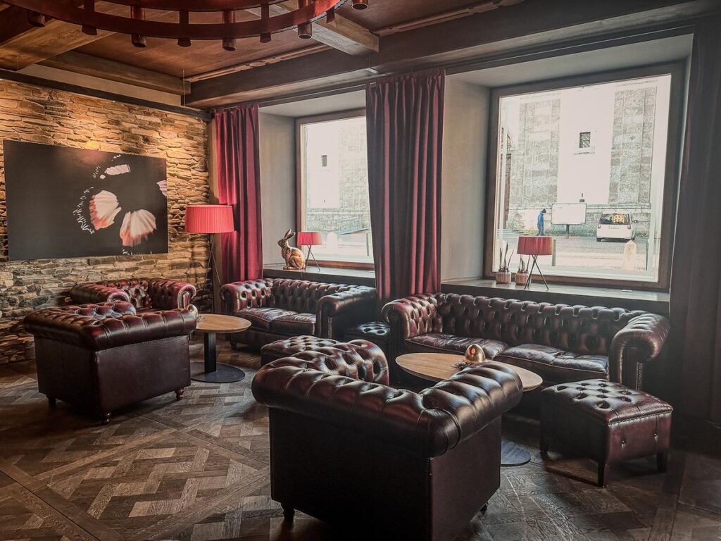 Luxurious Hotel Grauer Bär lobby with Chesterfield sofas, stone walls, and a view of Innsbruck's streets.