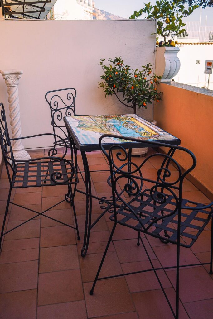 Hotel Villa Gabrisa patio with wrought iron chairs, ceramic tiled table, and potted kumquat tree in Positano, Italy.