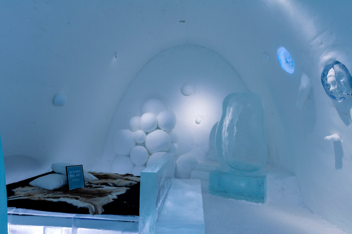 Hand-carved ice art surrounding a bed in an ICEHOTEL suite