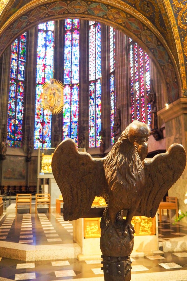 Interior view of Aachen Cathedral with stained glass windows and eagle lectern