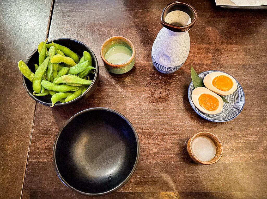 Edamame, sake, and seasoned egg served at Restaurant Kyo