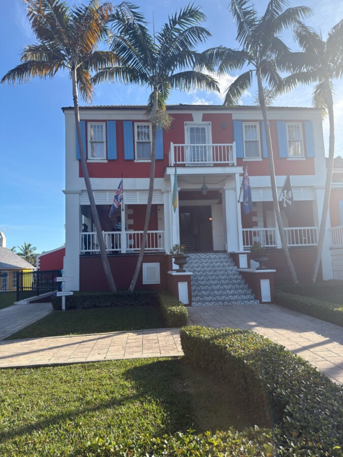 Red-and-white colonial buildings of John Watling's Distillery at the Buena Vista Estate in Nassau, framed by palm trees