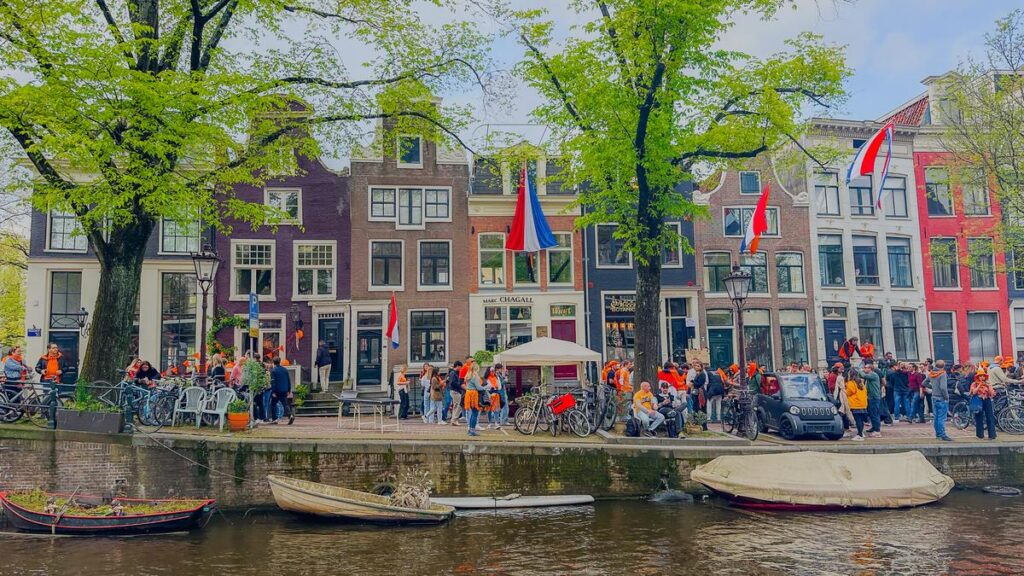 King's Day celebrations along Spiegelgracht in Amsterdam: vibrant orange festivities, Dutch flags, classic canal houses