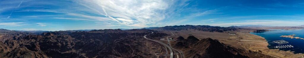 Panoramic view of Lake Mead with blue skies and rugged mountains from a scenic overlook.