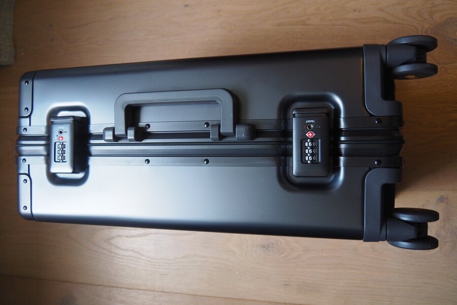 Two closed TSA latches, a side handle and paired spinner wheels line the aluminum carry-on frame.