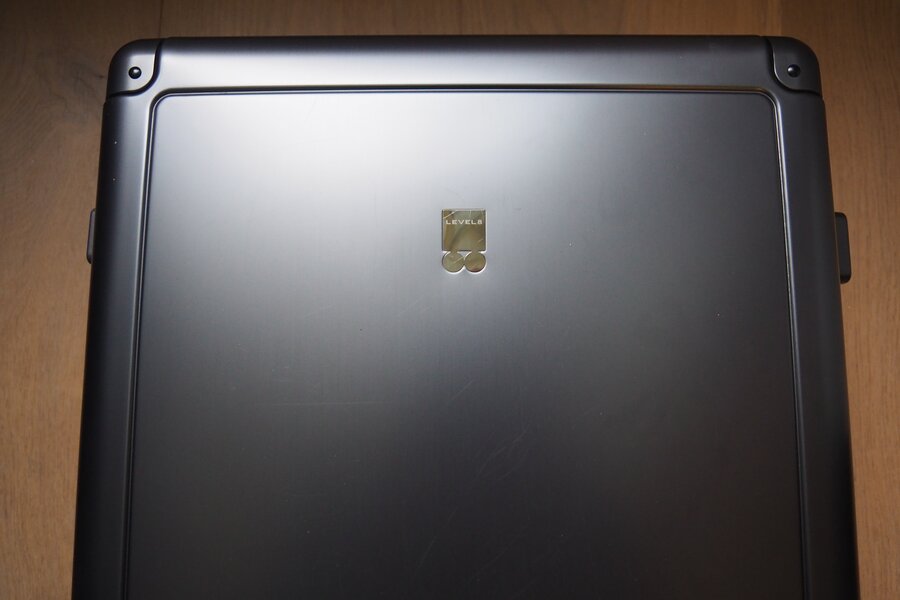 Fine scratches are visible on the grey aluminum carry-on around and below the LEVEL8 badge.