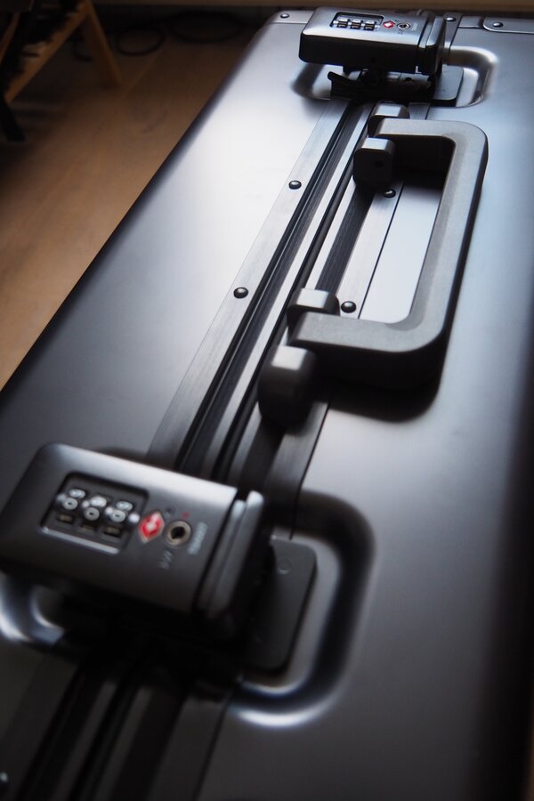 Two combination-lock latches flank the side carry handle on the LEVEL8 Gibraltar aluminum suitcase.