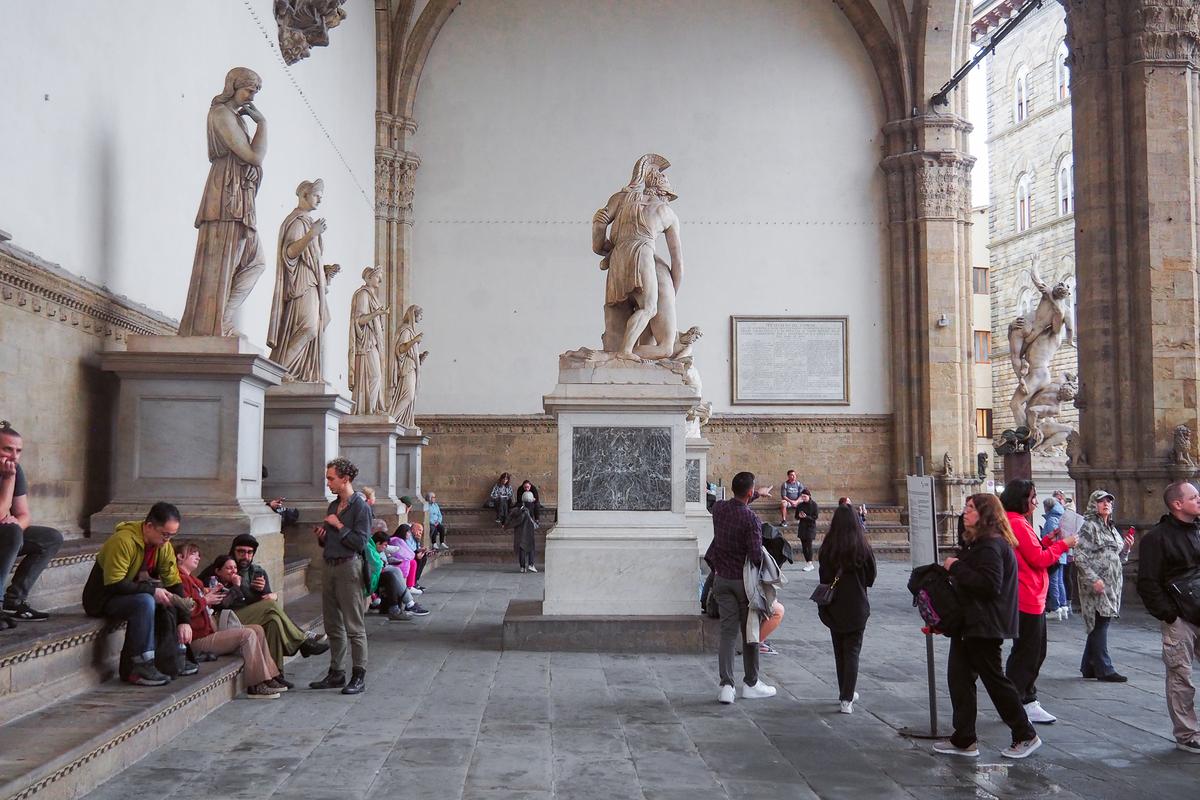 Tourists and statues at Loggia dei Lanzi in Florence, Italy - a vibrant snapshot of historic sculptures and modern-day observers.