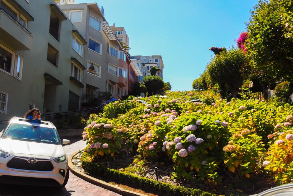 Lombard Street, San Francisco - iconic, winding road with lush greenery and blue sky, inviting exploration.