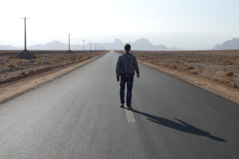 Stuart Jameson, a lone hitchhiker walking down the center of the road in Iran