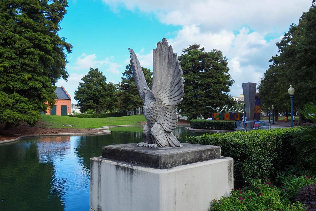 Eagle statue in Louis Armstrong Park New Orleans by pond with lush greenery in background