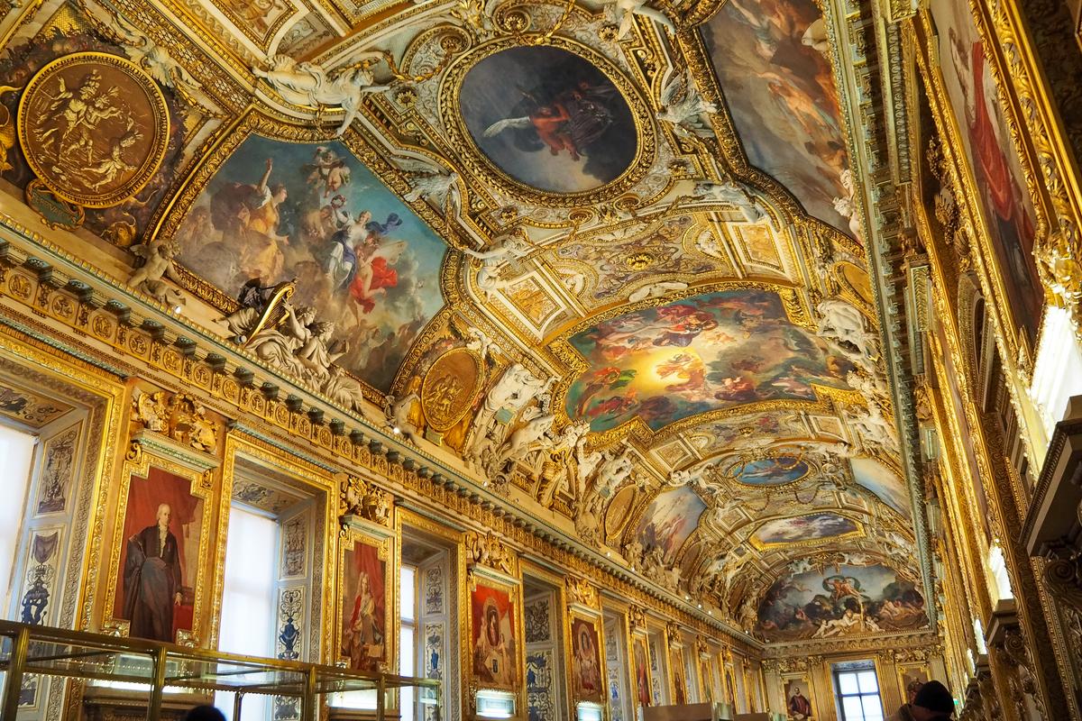 Ornate Louvre Museum interior with ceiling art and frescoes in Paris