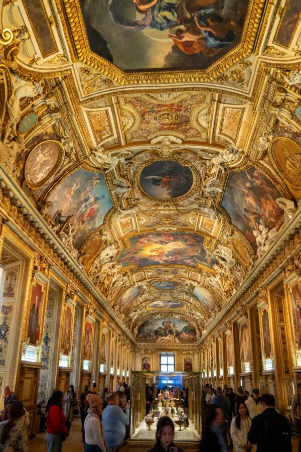 Louvre Museum gallery with visitors and Renaissance art in Paris