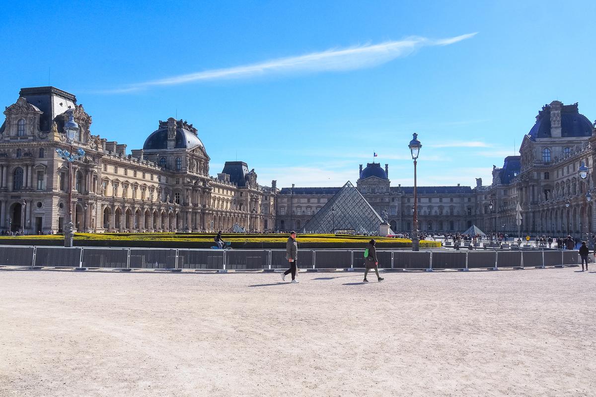 Louvre Museum with its iconic glass pyramid and visitors in Paris