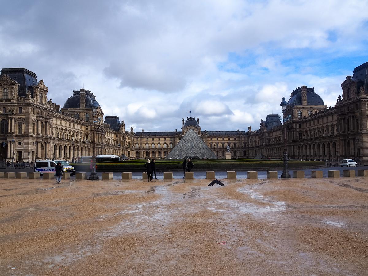 Louvre Museum Paris with iconic glass pyramid and visitors