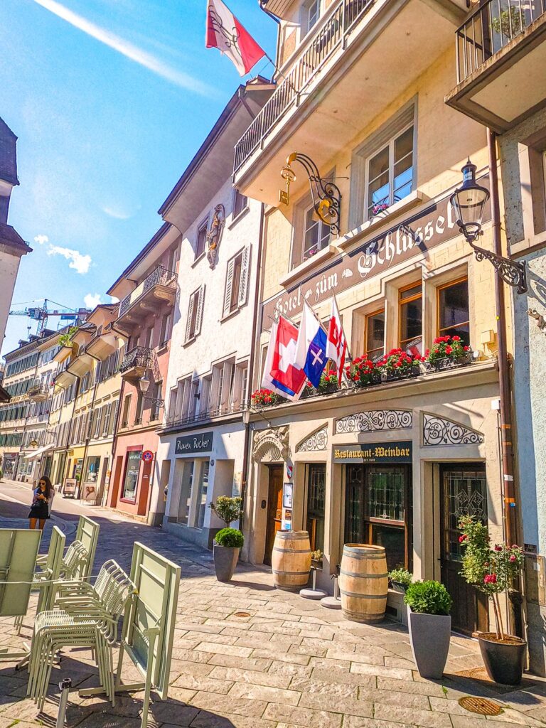 Charming Lucerne street with cobblestones, Swiss flags, and café