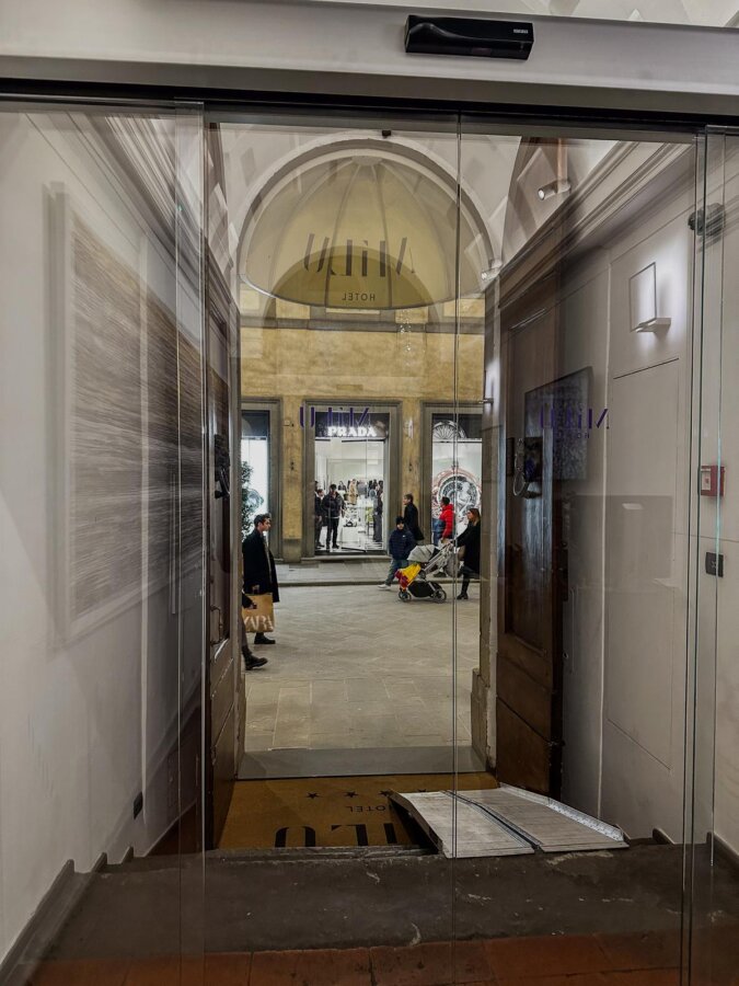 Elegant Hotel Milu entrance in Florence with reflections of bustling street life.