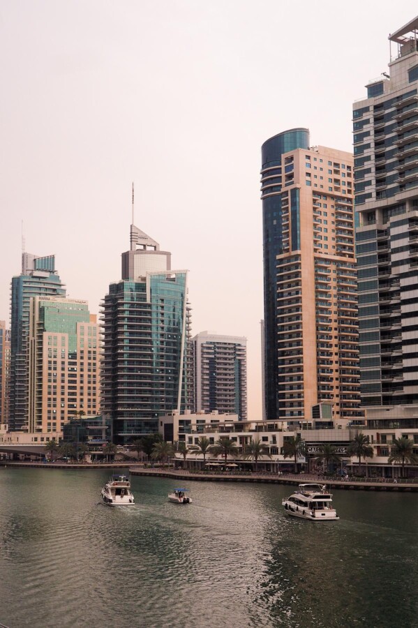 Luxury yachts sailing in Dubai Marina at dusk, with modern skyscrapers in the background.
