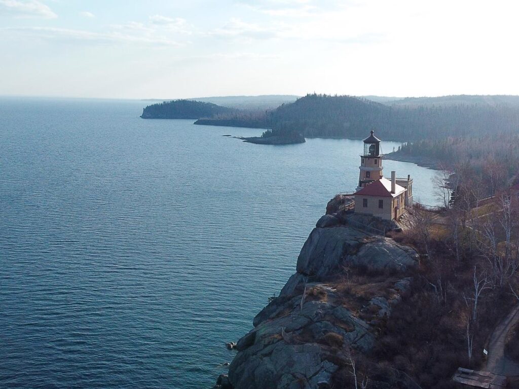 Aerial view of Split Rock Lighthouse on Lake Superior's North Shore, flanked by forest and open water.
