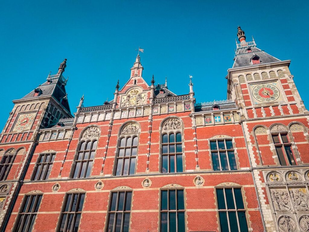 Amsterdam Centraal Station façade against clear blue sky.