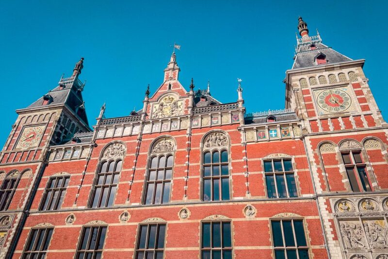 Amsterdam Centraal Station façade against clear blue sky.