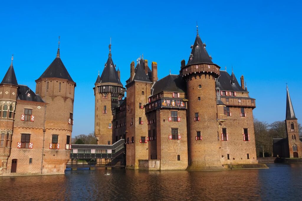 Castle De Haar on a sunny day, surrounded by moat, showcasing medieval architecture and vibrant colors.