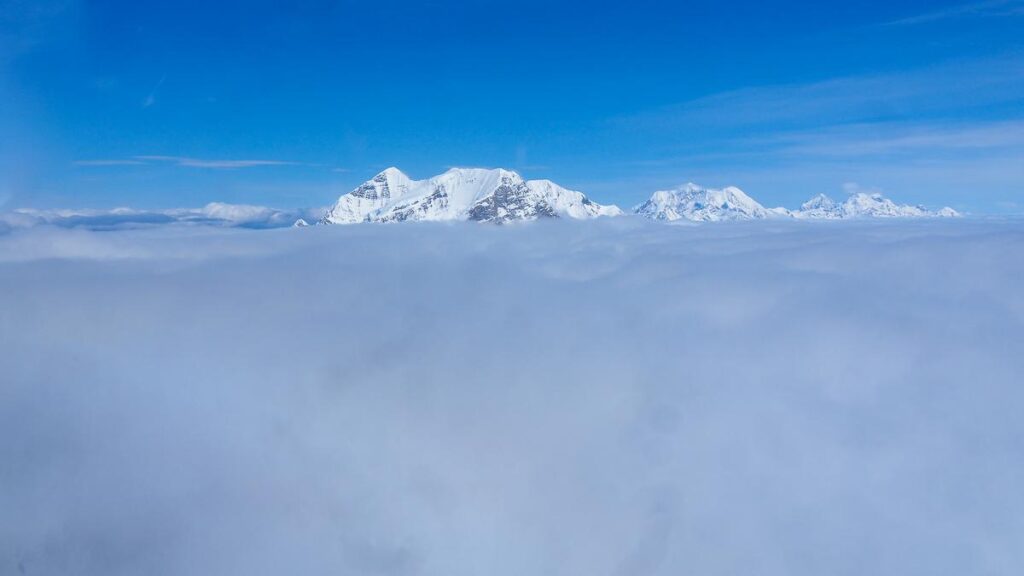 Mount Denali soaring above clouds on helicopter tour, showcasing Alaska's natural wonders.
