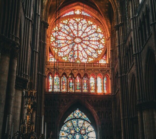 The captivating stained glass rose windows of Reims Cathedral, illuminated by sunlight within the Gothic interior.