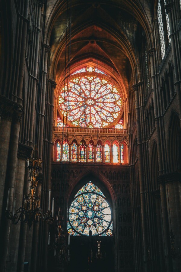 The captivating stained glass rose windows of Reims Cathedral, illuminated by sunlight within the Gothic interior.