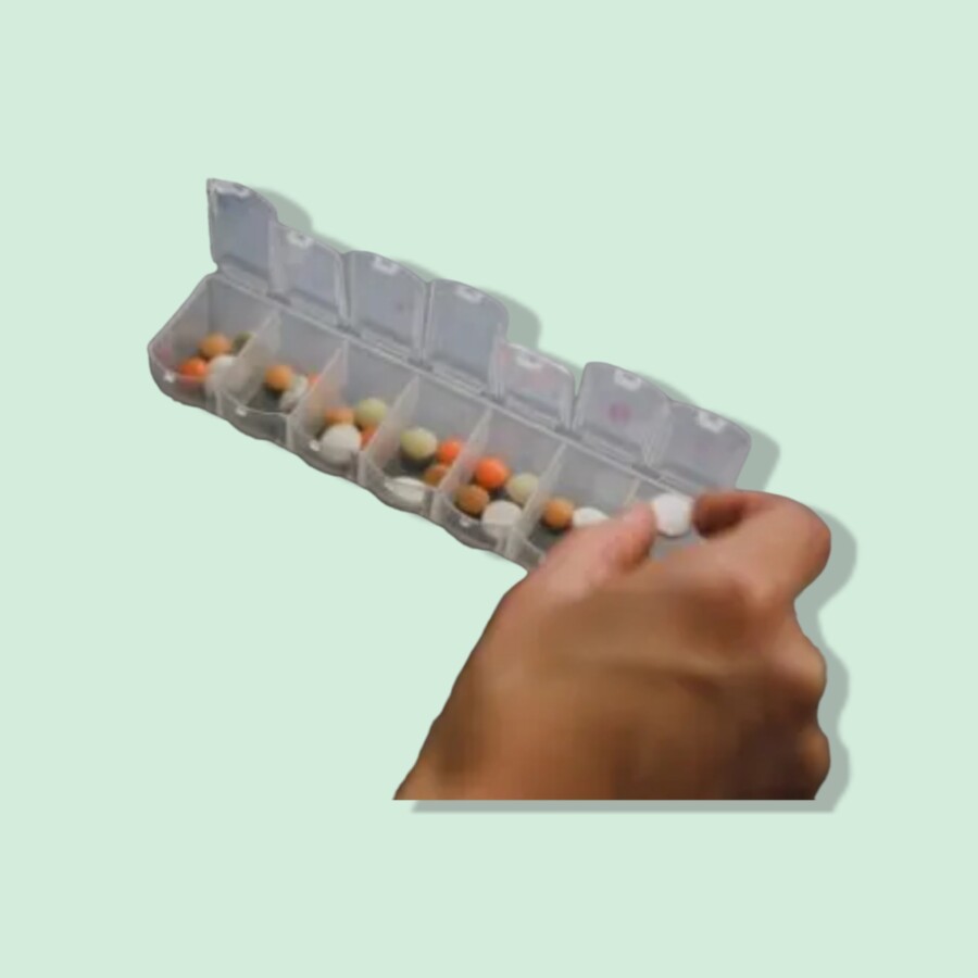 Hand holding a medicine container filled with pills and tablets