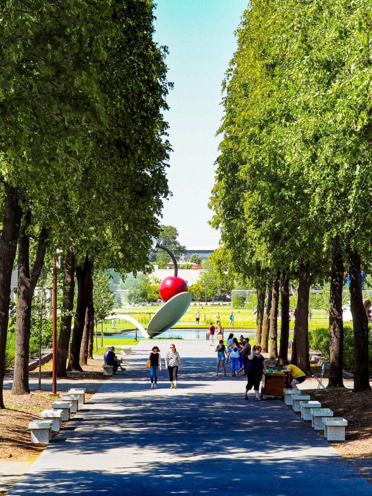 Minneapolis Sculpture Garden: Fusion of art and nature, iconic cherry and spoon sculpture, visitors exploring contemporary art and lush greenery.