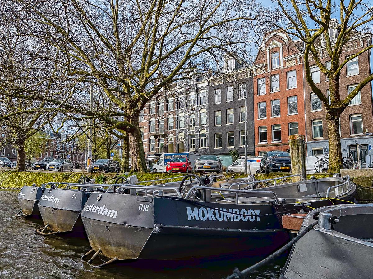 A fleet of Mokumboot rental boats lined along Amsterdam's serene canal