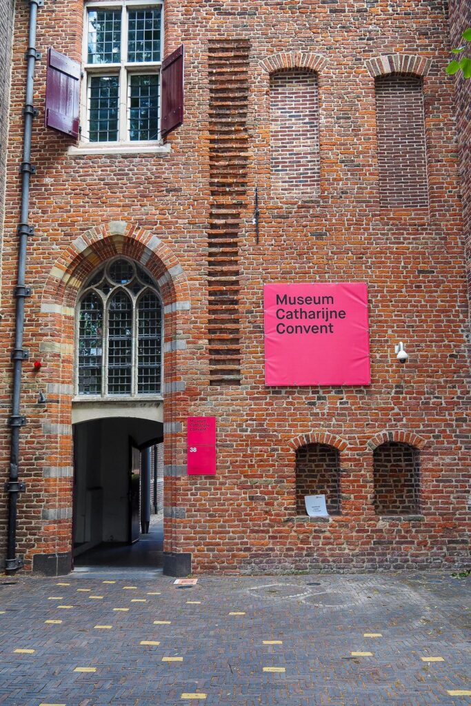 Museum Catharijneconvent entrance with magenta sign, red brick facade, and arched doorway in Utrecht, Netherlands.