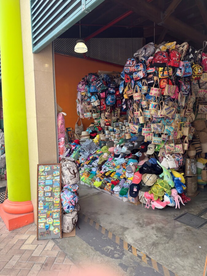 Souvenir stall at the Nassau Straw Market stacked with straw bags, Bahamas caps, T-shirts, and fridge magnets