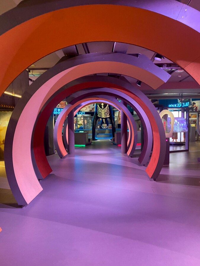 Visitors exploring interactive exhibits under colorful arches at NEMO Science Museum Amsterdam