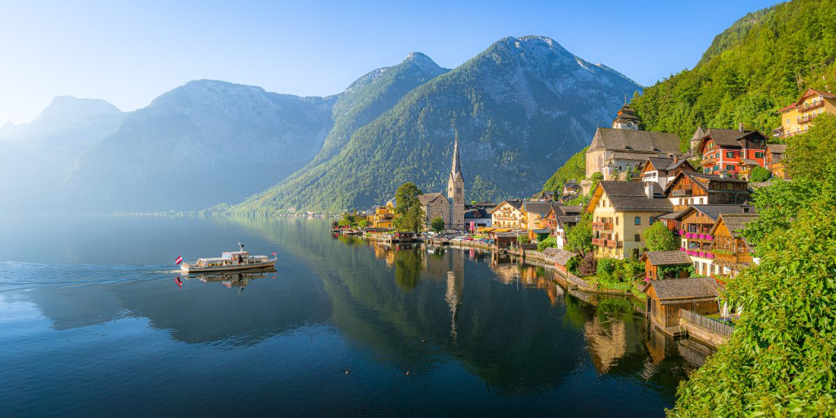 Old town Hallstatt and alpine deep blue lake with tourist ship
