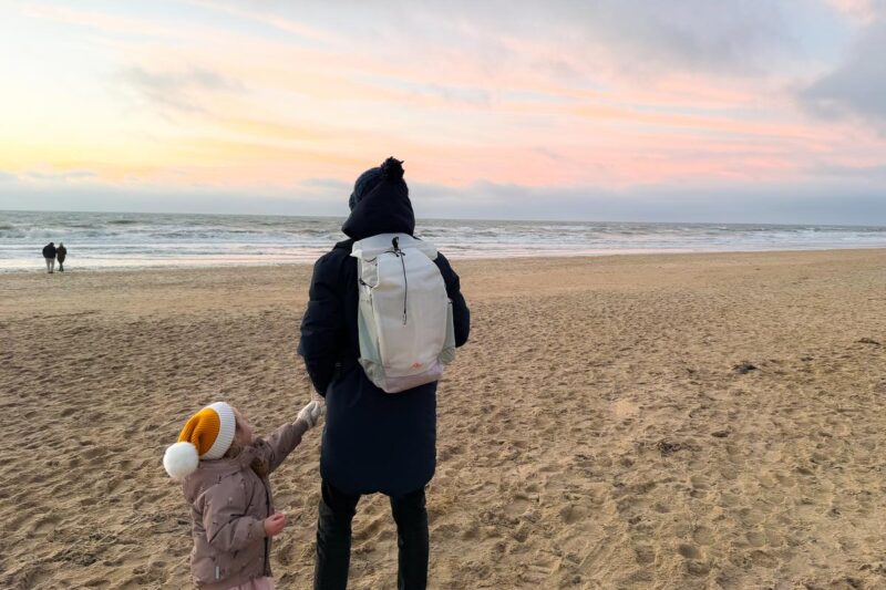 Family with Peak Design backpack walking on Dutch beach at sunset