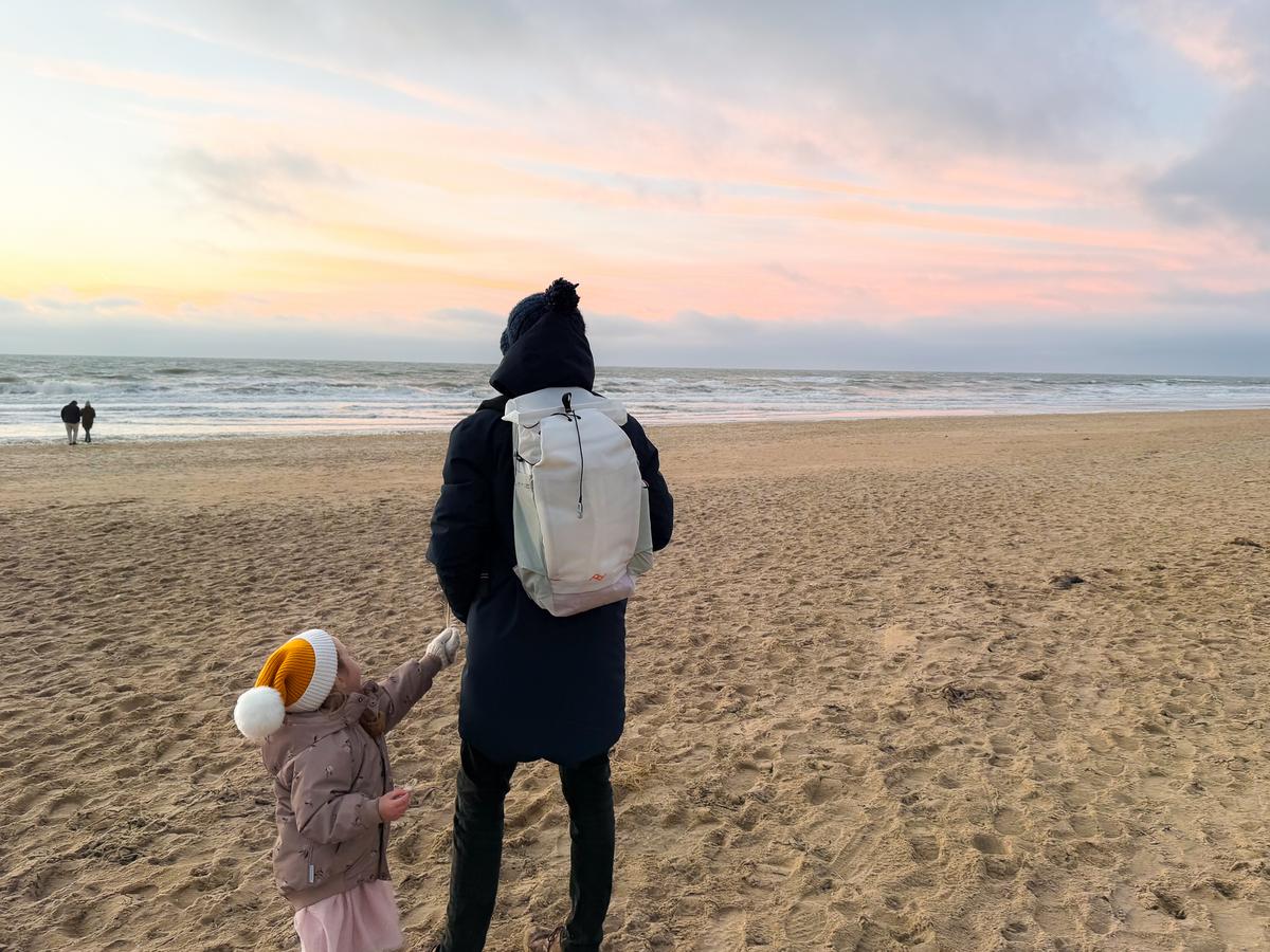 Family with Peak Design backpack walking on Dutch beach at sunset