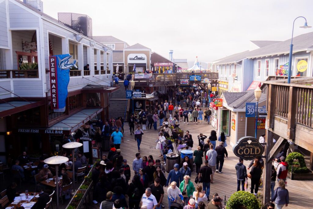 Pier 39, San Francisco: Vibrant waterfront scene with tourists, locals, colorful signage, and diverse dining options.
