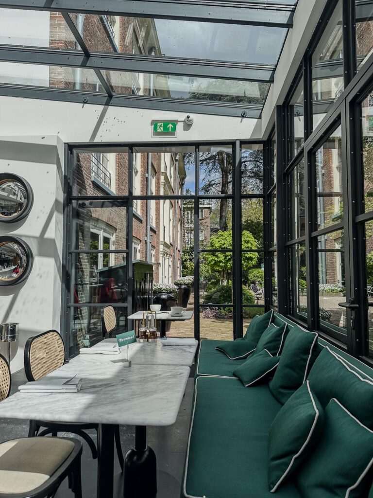 Serene elegance of Pulitzer Amsterdam Hotel's interior garden, blending modern design and historical charm with lush greenery.