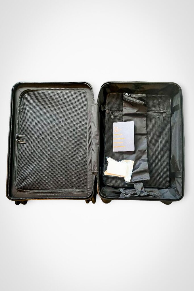 Quince hardshell suitcase with black textile lining, mesh divider, and storage compartments