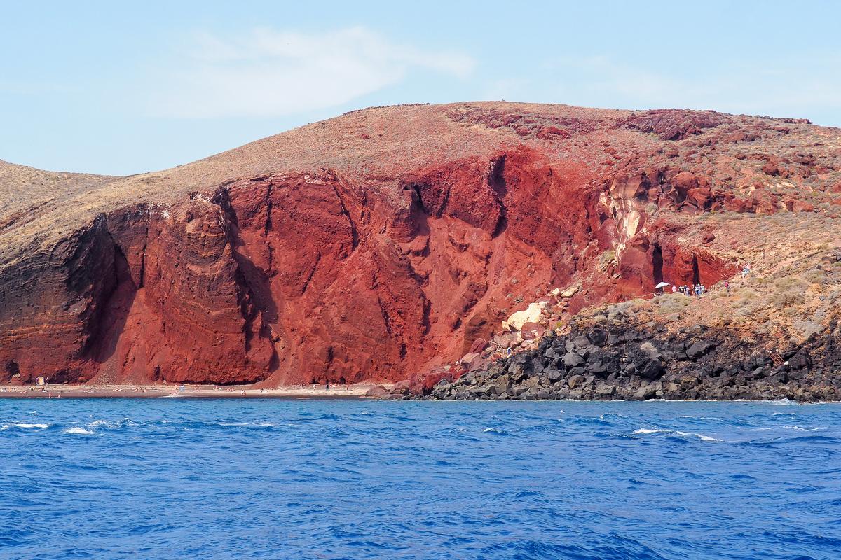 Stunning view of Red Beach Santorini from boat with vibrant cliffs and turquoise waters