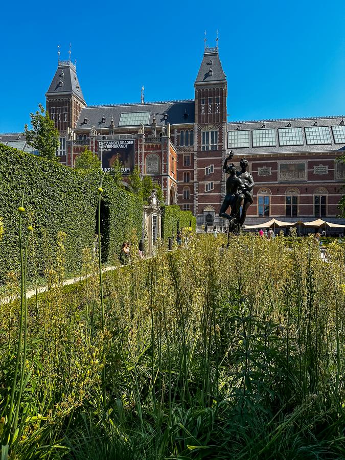 Rijksmuseum garden statues and lush greenery on a sunny day, Amsterdam