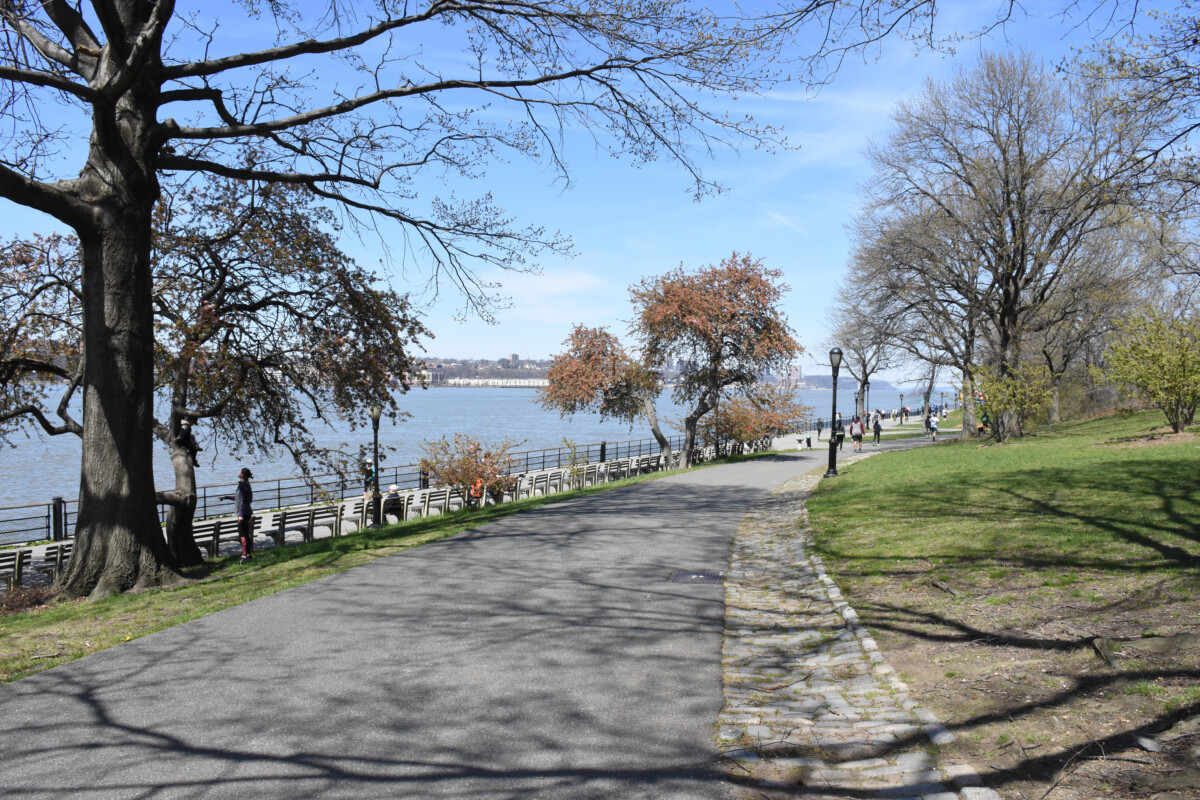 Huge pathway, trees, and benches on the side with the view of a river at Riverside Park, New York