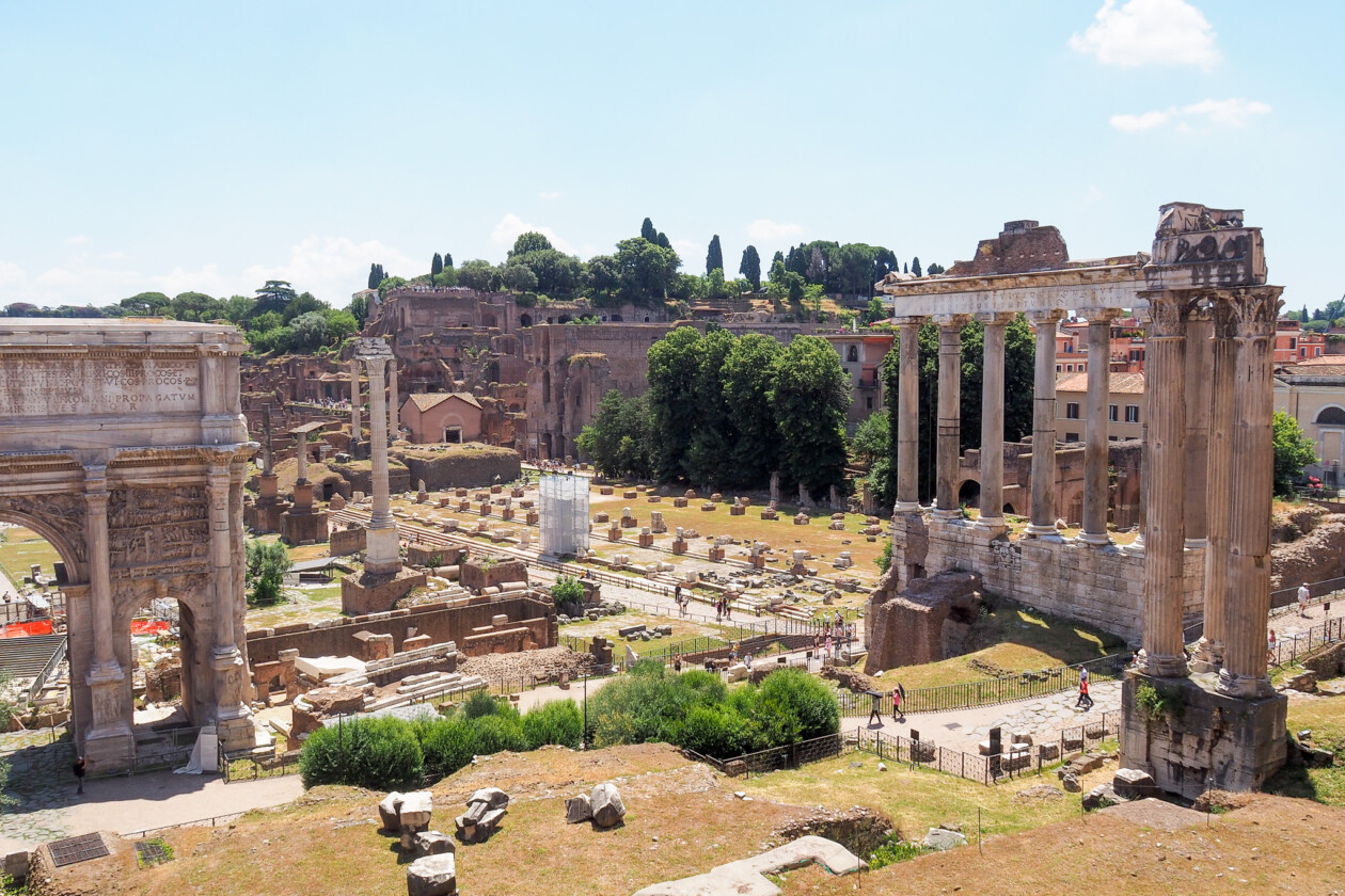 Roman Forum ruins with ancient columns and a triumphal arch in Rome