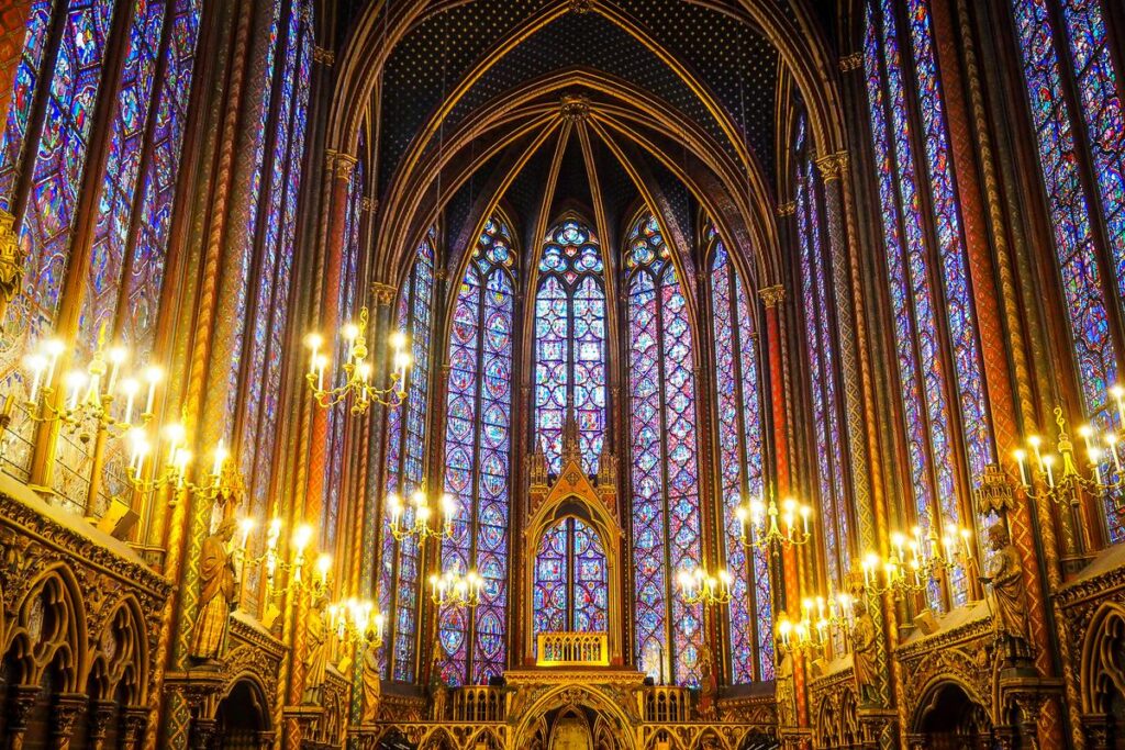 Alt-text: Interior of Sainte-Chapelle in Paris, showcasing vibrant stained glass, gothic columns, and ornate chandeliers.
