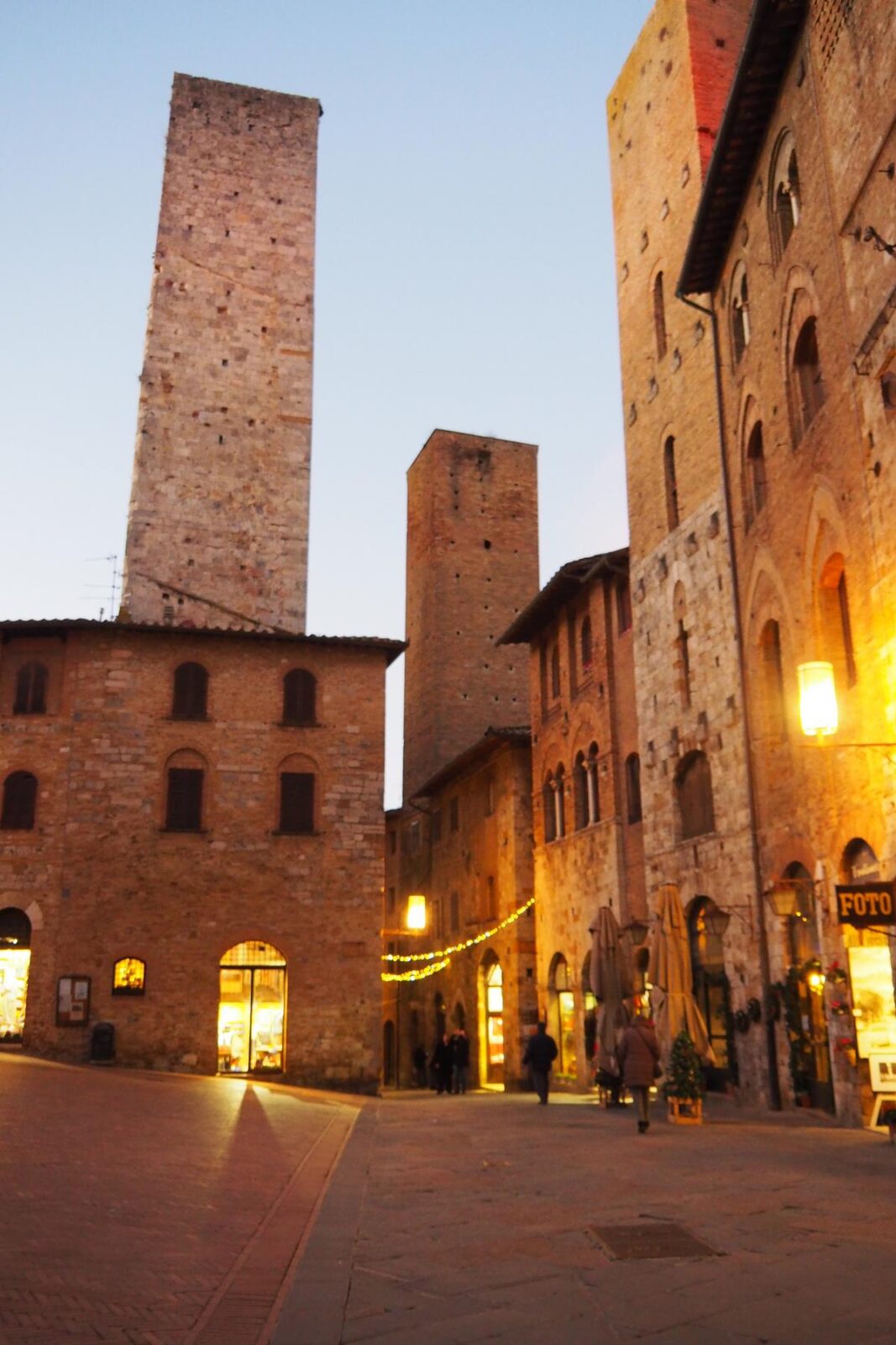 Twilight over historic San Gimignano center with illuminated medieval towers and shops
